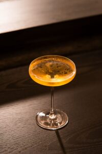 木質吧台上的金色調飲與高腳杯