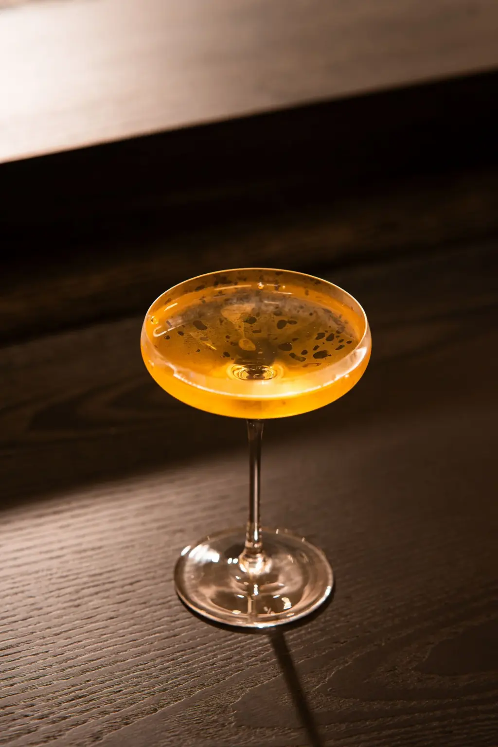 木質吧台上的金色調飲與高腳杯