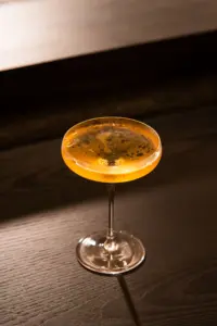 木質吧台上的金色調飲與高腳杯