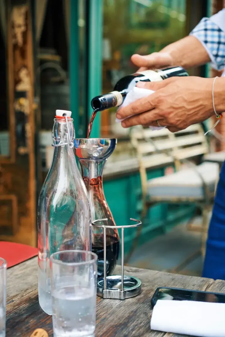 戶外餐桌旁將紅酒倒入玻璃醒酒器的動作