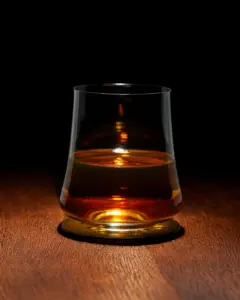 木桌上盛著琥珀色酒液的玻璃杯